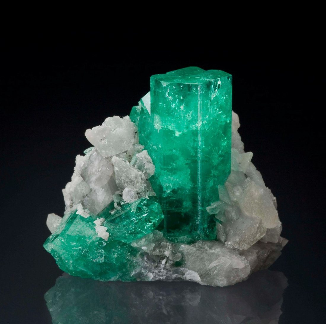 A lustrous emerald crystal cluster on matrix, representing the quality specimens Matesa curates